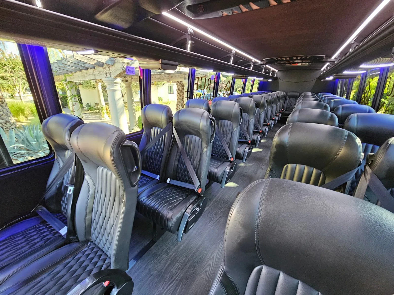 Interior of a True Elegance executive shuttle bus with black quilted leather seats, centre aisle and blue accent lighting