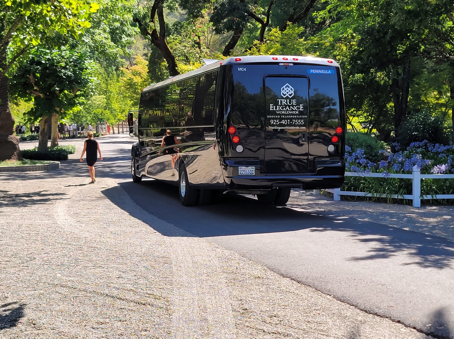 Black True Elegance mini motorcoach arriving on a tree-lined winery driveway for a group event — True Elegance charter bus rental in Tri-Valley, California