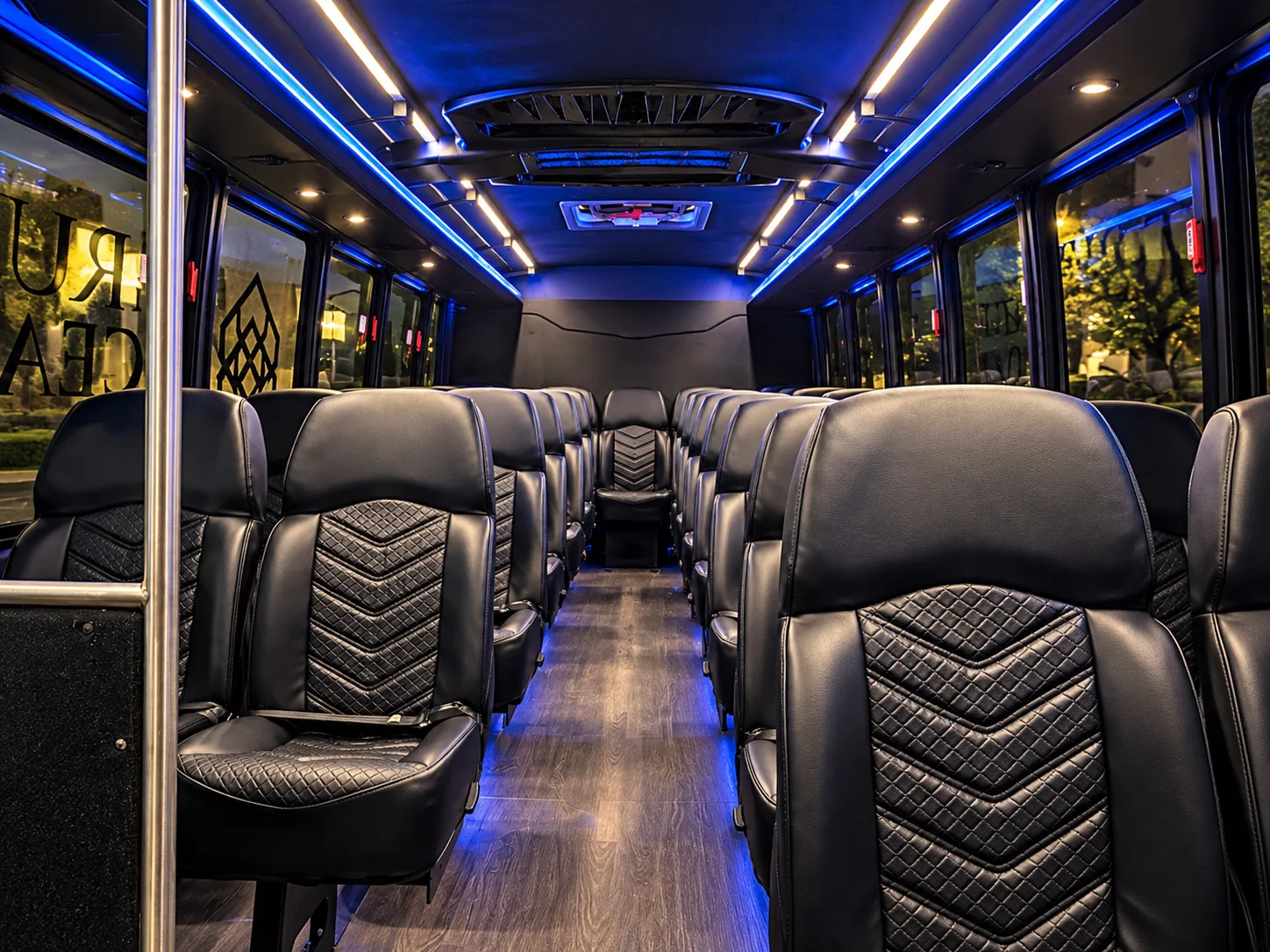 Interior of a True Elegance 27-passenger shuttle bus with black quilted leather seats, seatbelts and blue LED lighting, available for San Francisco limo service and corporate group transportation in the Bay Area, California